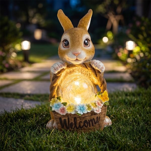 Solar rabbit garden statue with flower basket glowing at dusk